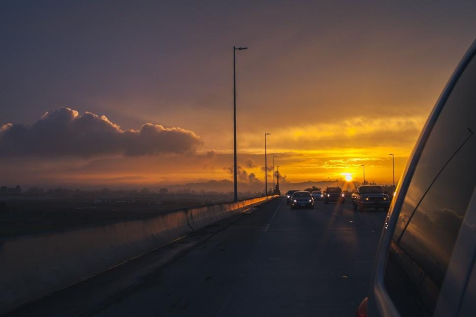 Sun setting over a USA highway with cars on a road trip